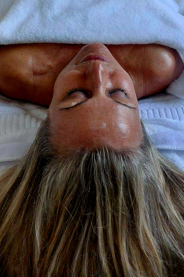 blundande kvinna med långt blont hår ligger på massagebänk för ansiktsbehandling